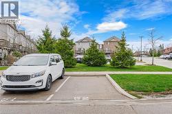 The property features a dedicated parking space with visible numbering, surrounded by well-maintained green spaces and mature evergreen trees - 