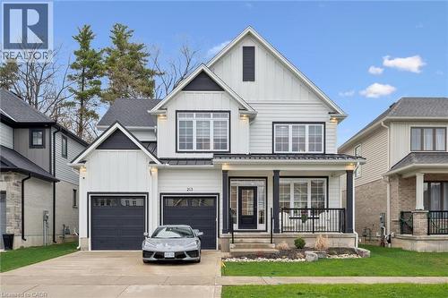 Contemporary two-story residence featuring a white and black exterior, multiple gables, and a prominent covered front porch with black railings - 213 Fallowfield Drive, Kitchener, ON - Outdoor With Facade