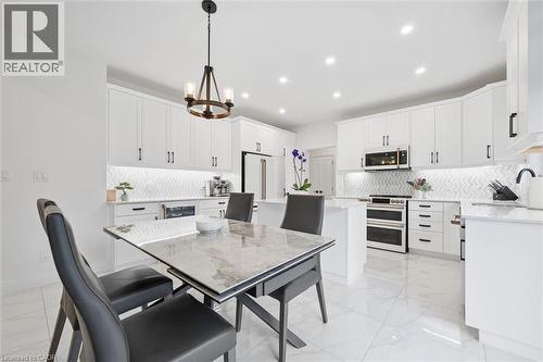 Bright kitchen featuring white cabinetry, stainless steel appliances, a white herringbone tile backsplash, and recessed lighting - 213 Fallowfield Drive, Kitchener, ON - Indoor