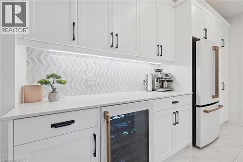 White cabinetry with black hardware, white countertops, and a chevron pattern tile backsplash - 213 Fallowfield Drive, Kitchener, ON - Indoor Photo Showing Kitchen