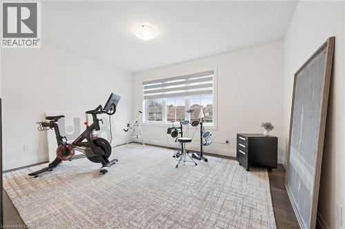 Bright room featuring a large window with blinds, dark wood-finish flooring, white baseboards, and a ceiling-mounted light fixture - 213 Fallowfield Drive, Kitchener, ON - Indoor Photo Showing Gym Room