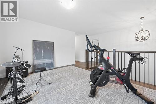 Open concept room featuring white walls, dark wood-finish flooring, and a modern light gray area rug - 213 Fallowfield Drive, Kitchener, ON - Indoor Photo Showing Gym Room