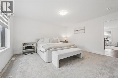Carpeted bedroom with a window featuring roller blinds, white walls, and a ceiling-mounted light fixture - 213 Fallowfield Drive, Kitchener, ON - Indoor Photo Showing Bedroom