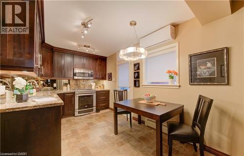 Kitchen and dining area featuring dark wood cabinetry, stainless steel appliances, granite countertops, and a window providing natural light - 48 Dupont Street, Waterloo, ON - Indoor