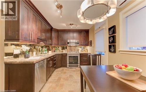 The kitchen features extensive dark wood cabinetry, granite countertops, and stainless steel appliances - 48 Dupont Street, Waterloo, ON - Indoor Photo Showing Kitchen