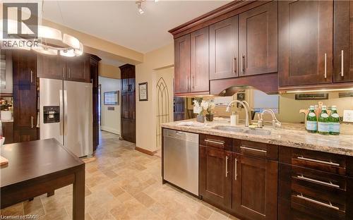The property features a kitchen with dark wood cabinetry, a stainless steel refrigerator, and a stainless steel dishwasher - 48 Dupont Street, Waterloo, ON - Indoor Photo Showing Kitchen With Double Sink