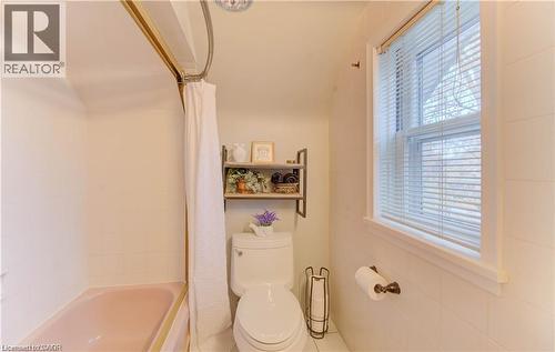 The bathroom features a bathtub, a toilet, and a window with blinds providing natural light - 48 Dupont Street, Waterloo, ON - Indoor Photo Showing Bathroom