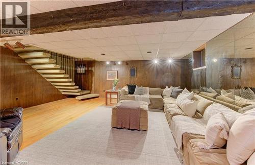 Recreation room featuring exposed wood ceiling beams, wood paneling, and a stairway with a metal railing - 48 Dupont Street, Waterloo, ON - Indoor Photo Showing Basement