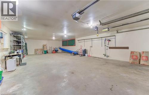 Expansive garage space featuring a concrete floor, bright overhead lighting, and track-mounted overhead garage door openers - 48 Dupont Street, Waterloo, ON - Indoor Photo Showing Garage