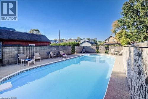 The property features an outdoor swimming pool with a surrounding paved patio area - 48 Dupont Street, Waterloo, ON - Outdoor With In Ground Pool