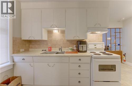 The kitchen features white cabinetry, a double basin sink, and a white electric range with an overhead exhaust fan - 48 Dupont Street, Waterloo, ON - Indoor Photo Showing Kitchen
