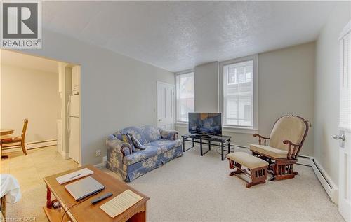 The living area features neutral-toned walls, carpeted flooring, and two windows with blinds - 48 Dupont Street, Waterloo, ON - Indoor Photo Showing Living Room