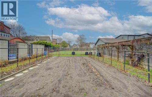 The property features an expansive garden area with cultivated soil, bordered by a metal fence and a trellis structure - 48 Dupont Street, Waterloo, ON - Outdoor