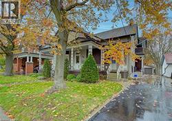 Charming property exterior featuring a covered front porch with decorative railing, a well-maintained lawn, and a paved driveway leading to a detached garage - 