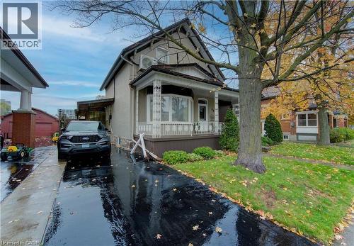 The property features a classic architectural style with a covered front porch and bay window - 48 Dupont Street, Waterloo, ON - Outdoor With Deck Patio Veranda