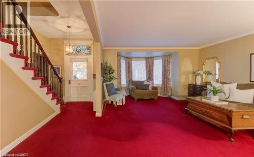 Living area featuring a grand staircase with a wooden banister, a bay window, and a front entry door with a stained glass transom - 48 Dupont Street, Waterloo, ON - Indoor Photo Showing Other Room