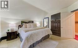 This room features a vaulted ceiling, light-colored carpeting, and a white paneled door - 