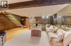 Recreation room featuring exposed wood ceiling beams, wood paneling, and a stairway with a metal railing - 