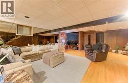 Spacious recreation room featuring wood paneling, light wood flooring, and a brick accent wall - 