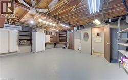 Finished basement with painted concrete flooring, exposed wood beam ceiling, and fluorescent lighting - 