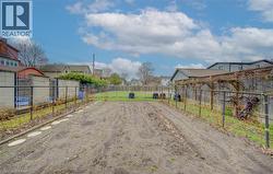The property features an expansive garden area with cultivated soil, bordered by a metal fence and a trellis structure - 