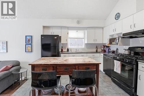 The property features a kitchen with white cabinetry, black appliances, and a wood-topped island - 110 Milton Avenue, Cambridge, ON - Indoor Photo Showing Kitchen