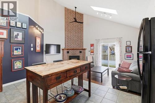 This bright living area features a brick fireplace, a skylight, and direct access to the outdoor space through sliding glass doors - 110 Milton Avenue, Cambridge, ON - Indoor Photo Showing Other Room