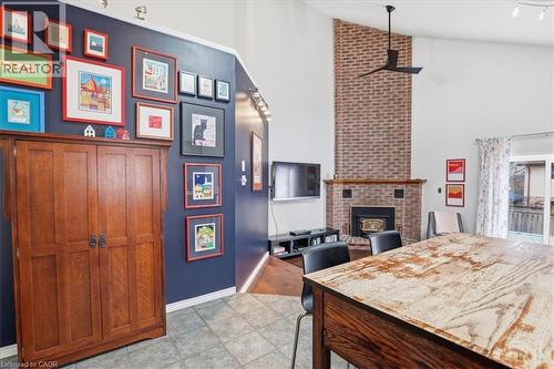The living area features a high vaulted ceiling, a brick fireplace, and tiled flooring - 110 Milton Avenue, Cambridge, ON - Indoor With Fireplace