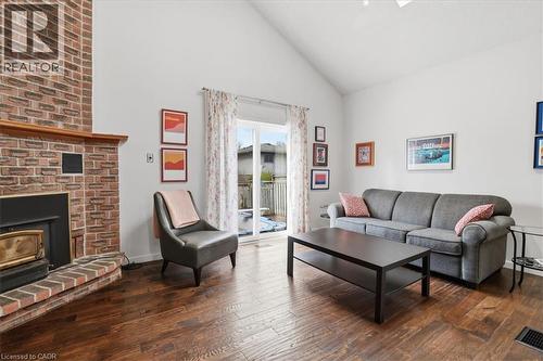 Living area featuring high ceilings, hardwood flooring, a brick fireplace with a wood mantle, and sliding glass doors leading to a deck - 110 Milton Avenue, Cambridge, ON - Indoor Photo Showing Living Room With Fireplace