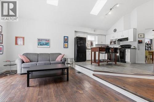 Open-concept living area featuring vaulted ceilings, skylights, rich wood flooring, and a kitchen with white cabinetry and black appliances - 110 Milton Avenue, Cambridge, ON - Indoor Photo Showing Living Room