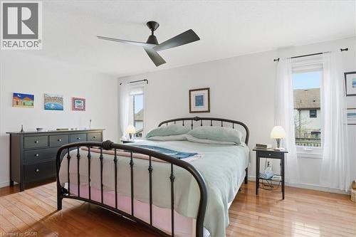 The room features hardwood floors, a ceiling fan, and two windows allowing for natural light - 110 Milton Avenue, Cambridge, ON - Indoor Photo Showing Bedroom
