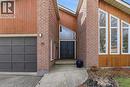 The property features a brick and wood facade, a prominent dark gray garage door, and a double entry door with an overhead triangular window - 110 Milton Avenue, Cambridge, ON  - Outdoor With Exterior 