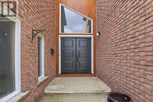 The property features a brick exterior with a prominent double door entrance, complemented by an angular transom window - 110 Milton Avenue, Cambridge, ON - Outdoor With Exterior