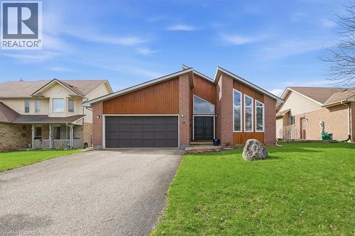 The property features a brick and wood facade, a two-car garage, and a well-maintained lawn - 110 Milton Avenue, Cambridge, ON - Outdoor With Facade