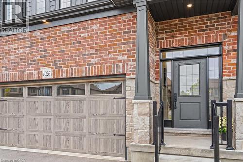 Brick and stone facade featuring a wood-finish garage door with upper windows and decorative hardware - 1026 Wright Drive, Midland, ON - Outdoor
