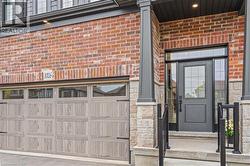 Brick and stone facade featuring a wood-finish garage door with upper windows and decorative hardware - 