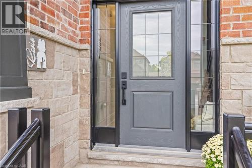 Front entry featuring a paneled door with glass inserts, sidelights, brick and stone facade, and black metal railings - 1026 Wright Drive, Midland, ON - Outdoor With Exterior