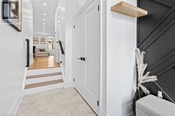 Entryway featuring tile flooring, white paneled doors with matte black hardware, and a decorative wall panel - 