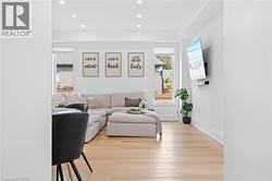 Bright open-concept living area featuring light wood-finish flooring, recessed lighting, and crisp white walls - 