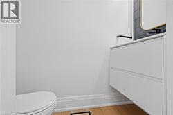 Modern powder room featuring a floating vanity with a white countertop, matte black wall-mounted faucet, and a contemporary mirror with a gold-tone frame - 