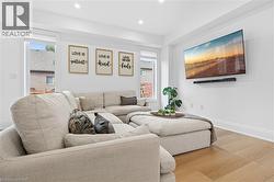 Bright living area featuring wood-finish flooring, recessed lighting, and crisp white walls - 