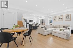 Open-concept living space featuring wood-finish flooring, recessed lighting, white walls, a kitchen with an island, and a sliding glass door to exterior - 