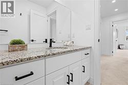 Double vanity with granite countertop, integrated sinks, white cabinetry, and matte black hardware - 