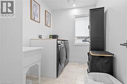 Dedicated laundry area featuring a utility sink, light wood-finish countertop, and tiled flooring - 