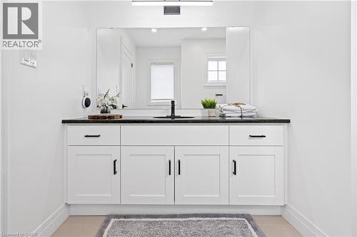 Modern bathroom vanity featuring white shaker cabinetry with black hardware, a dark countertop, an undermount sink with a matte black faucet, and a large mirror - 1026 Wright Drive, Midland, ON - Indoor Photo Showing Bathroom