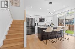 Modern kitchen featuring white cabinetry, stainless steel appliances, and a dark-toned island with a light-colored countertop - 