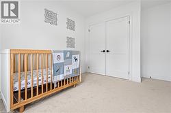 Carpeted room featuring white walls, a white baseboard, and a pair of white double doors with matte black hardware - 