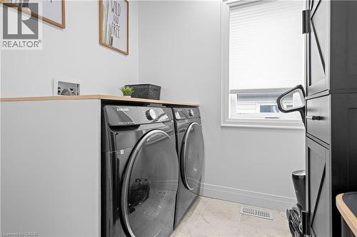 Dedicated laundry area featuring a light wood-finish countertop, white walls, light-toned floor tiling, and a window with a privacy blind - 1026 Wright Drive, Midland, ON - Indoor Photo Showing Laundry Room