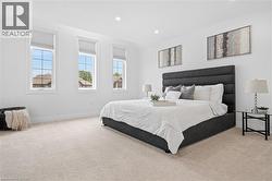 Bright room featuring three tall windows with white frames and blinds, recessed lighting, neutral tone carpet, and white baseboards - 