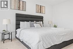 Spacious sleeping area featuring a tall, upholstered headboard, crisp white walls, and soft carpet flooring - 